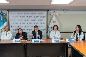 Cinco funcionarios sentados ante una mesa con micrófonos y letreros con nombres, frente a un fondo con logotipos del Ministerio de Salud