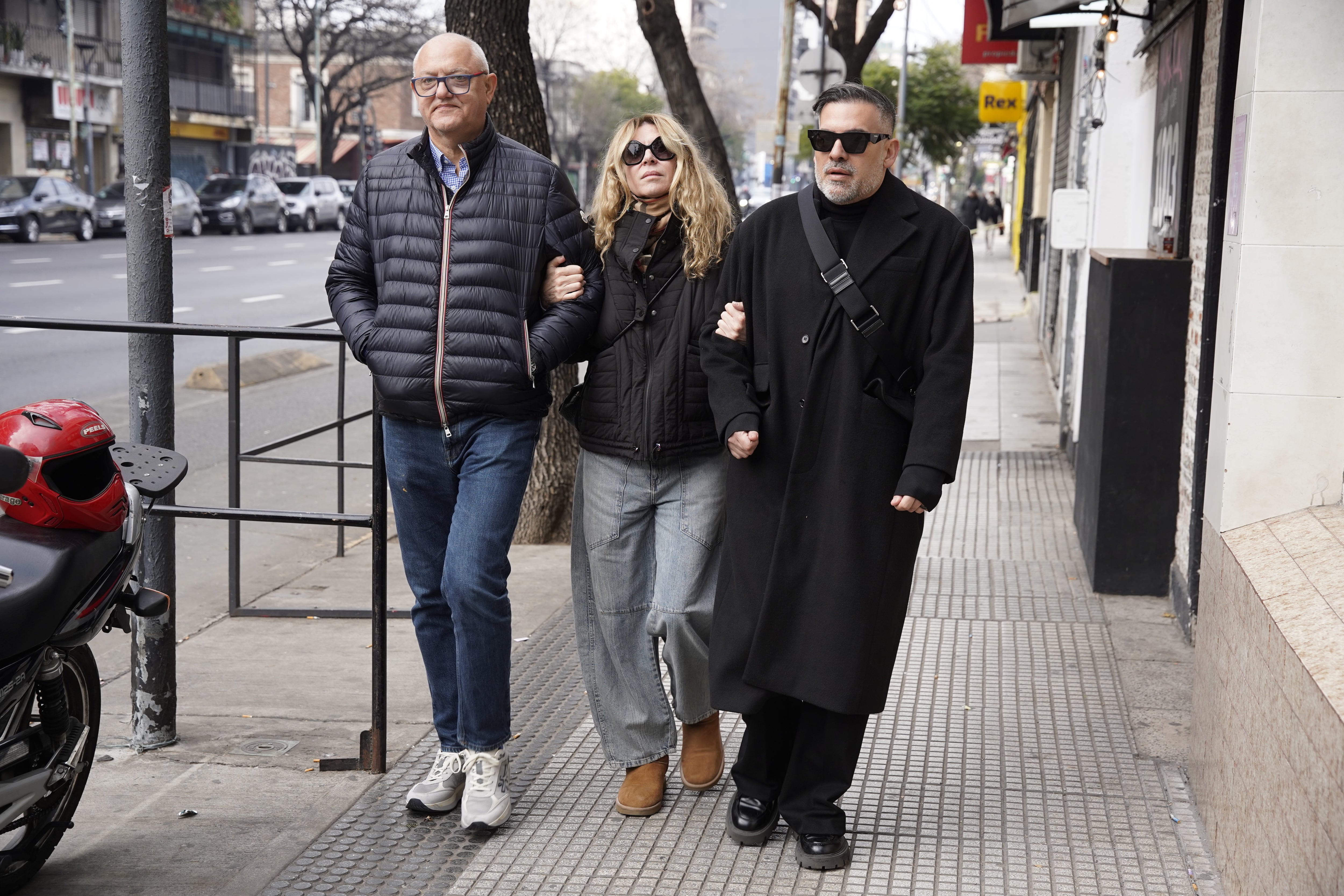 María Carámbula camina por una calle de la ciudad acompañada por dos hombres al llegar al velatorio de Ernestina Pais.