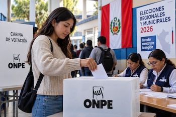 Una mujer deposita un documento en una urna con el logo de la ONPE, junto a una cabina de votación y un afiche sobre las elecciones 2026