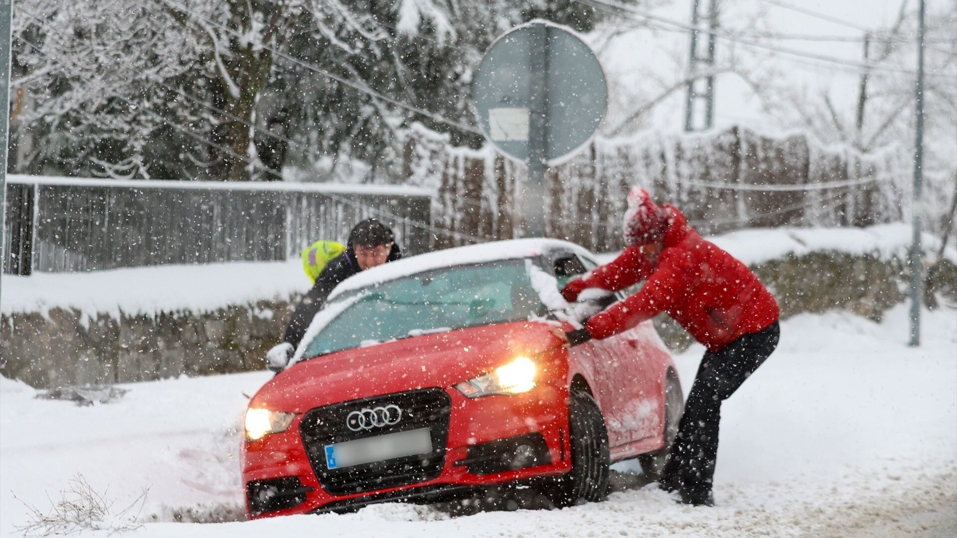 Varias personas tratan de sacar un coche de la nieve, a 28 de enero de 2026, en Madrid (Marta Fernández / Europa Press)