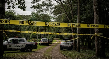 Tres vehículos patrulla de la Policía de Costa Rica en un camino de tierra, una cinta amarilla con la inscripción "NO PASAR" y densa vegetación tropical.