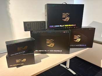 Seis cajas negras con logotipos dorados y motivos de consola portátil situadas sobre una mesa clara en una sala