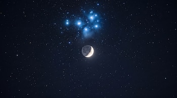 La Luna en cuarto menguante y el cúmulo estelar de las Pléyades brillan juntos en el cielo nocturno.
