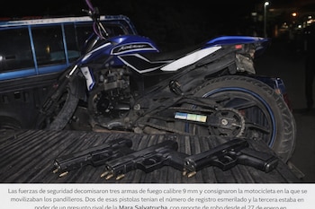 Tres pistolas con proyectiles en el cargador, una motocicleta azul y negra, y la caja de una camioneta azul, en una escena nocturna.