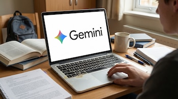 Una persona joven vista desde el hombro derecho usando una laptop con el logo de Gemini en la pantalla, rodeada de libros, cuadernos y una taza sobre un escritorio de madera.