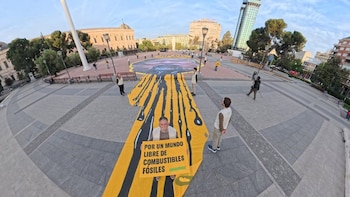 Activistas de Greenpeace despliegan una pancantar gigante de Trump vomitando petróleo en la plaza de Colón de Madrid