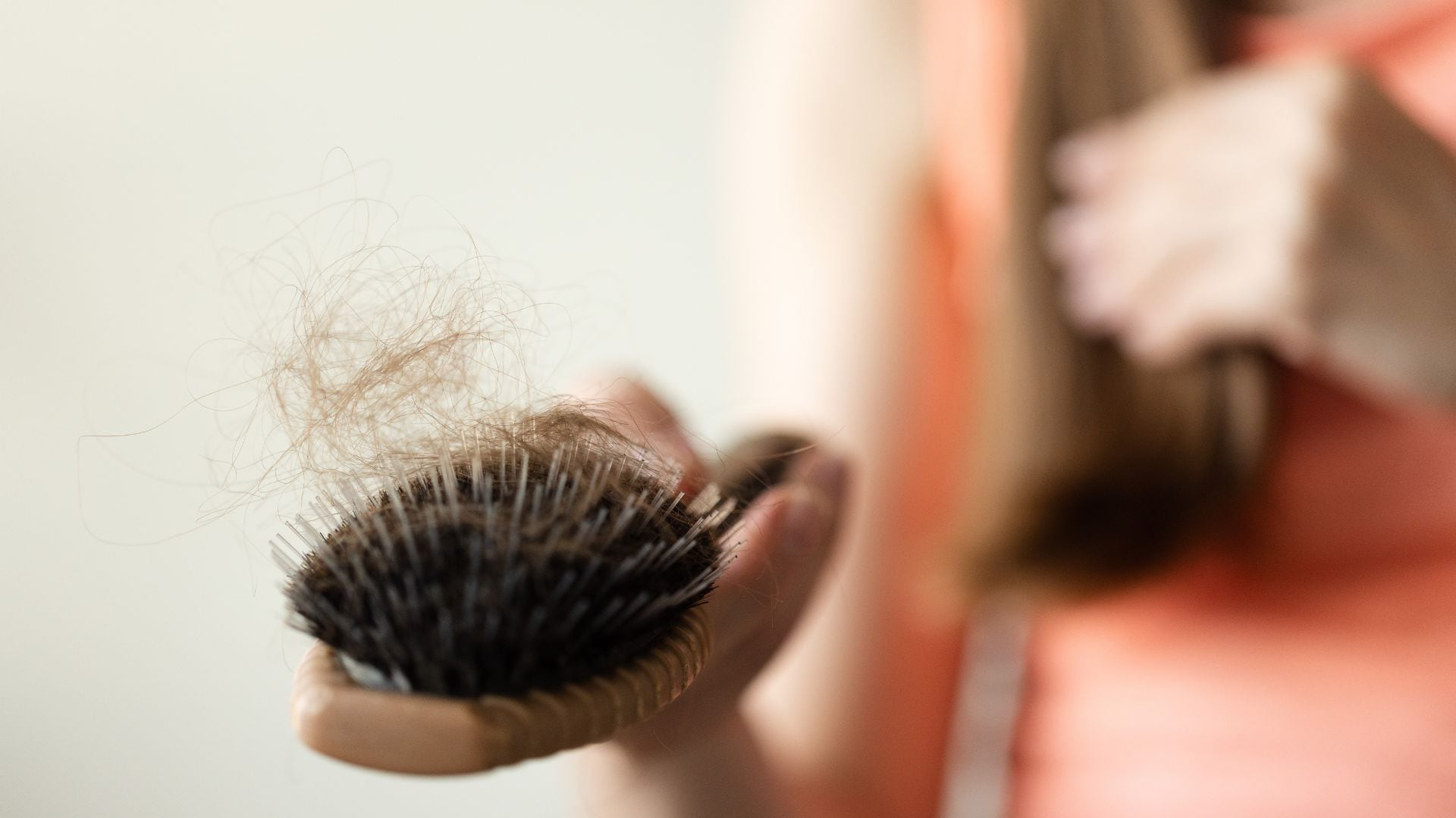 Una mujer sostiene un cepillo con varios mechones de cabello (Canva)
