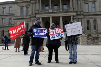 Un partidario de Trump y uno de Biden sostienen carteles frente al Capitolio del Estado de Michigan en Michigan. REUTERS/Emily Elconin