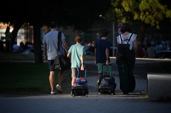 Dos niños salen del colegio y pasean junto a sus padres. (Fernando Sánchez / Europa Press)