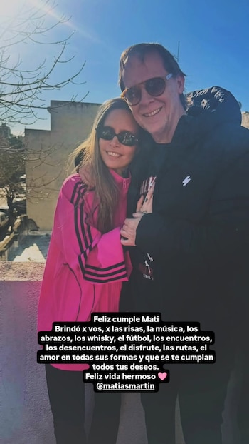 Una mujer con chaqueta deportiva fucsia y un hombre con abrigo negro y gafas de sol se abrazan al aire libre con un texto superpuesto