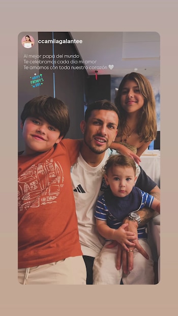 Un hombre sonriente abraza a tres niños, dos varones y una niña. El hombre viste una camiseta blanca con detalles negros y azules. Los niños sonríen
