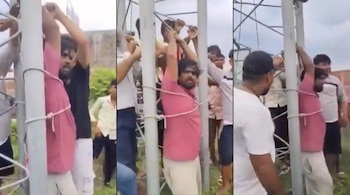 Tres imágenes verticales de un hombre con camiseta rosada atado con cuerdas a un poste metálico, rodeado por otros hombres al aire libre.