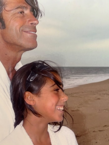 Nicolás Repetto y su hija Renata aparecen de perfil sonriendo en una playa frente al mar