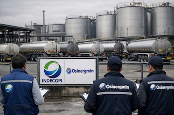 Tres inspectores de espaldas observan una planta de combustible con grandes tanques de almacenamiento y camiones cisterna, junto a un cartel de INDECOPI y OSINERGMIN.