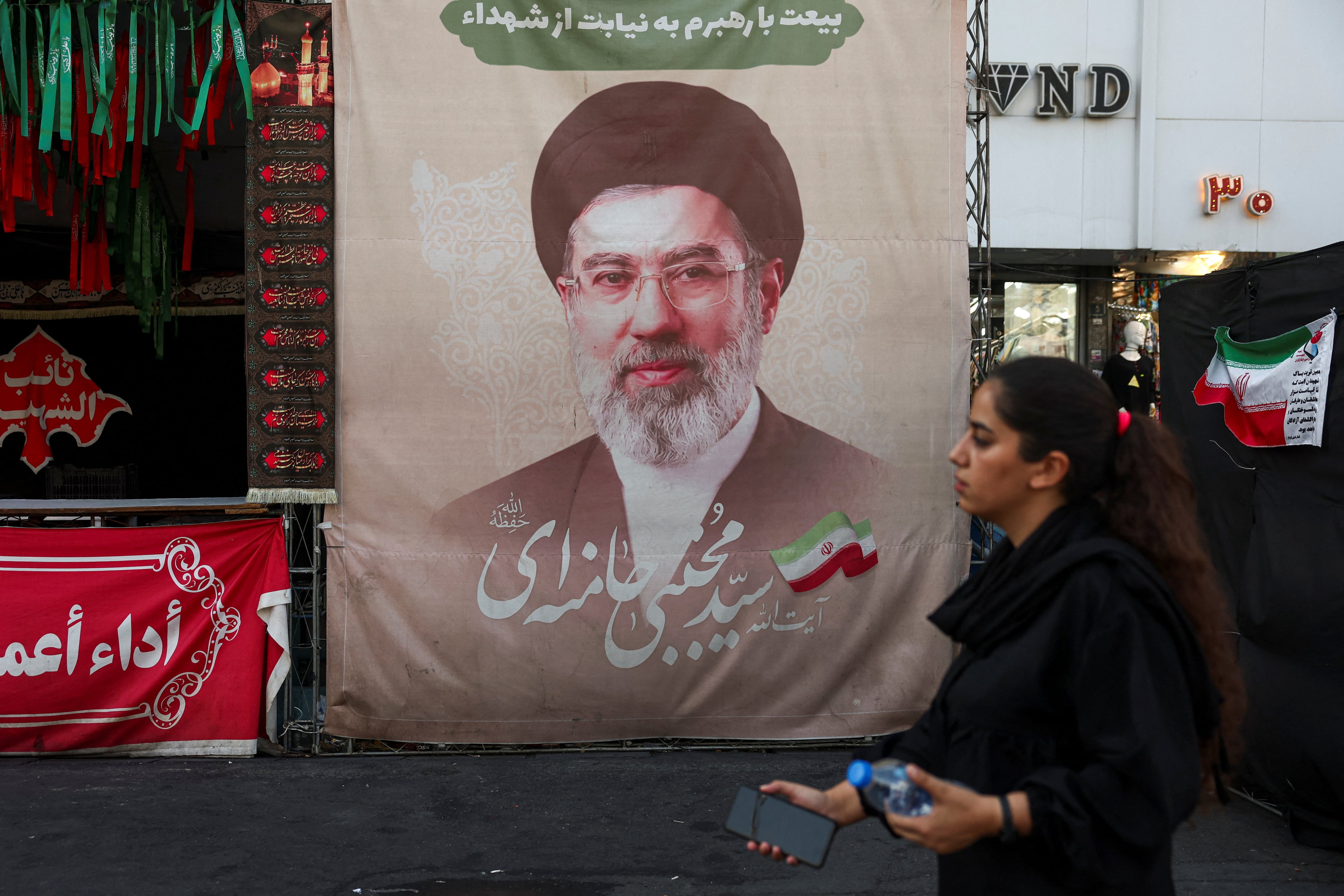 Una mujer camina junto a una pancarta con la imagen del líder supremo de Irán, Mojtaba Jamenei, quien no ha sido visto en público desde que asumió el cargo, en una calle de Teherán (Majid Asgaripour/WANA vía REUTERS/archivo)