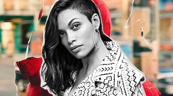 Retrato en blanco y negro de Rosario Dawson con aretes de aro sobre un fondo con una figura de Spider-Man en rojo y un fondo borroso.