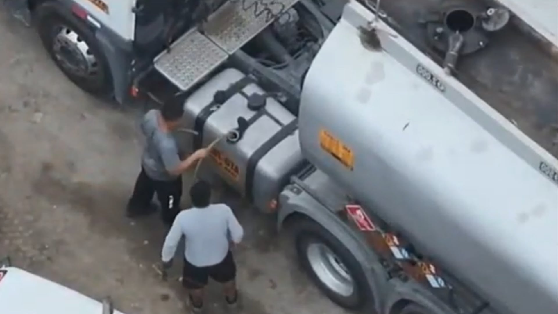 Dos hombres trasiegan combustible de un camión cisterna, como parte del operativo que permitió a la Policía Nacional desarticular a