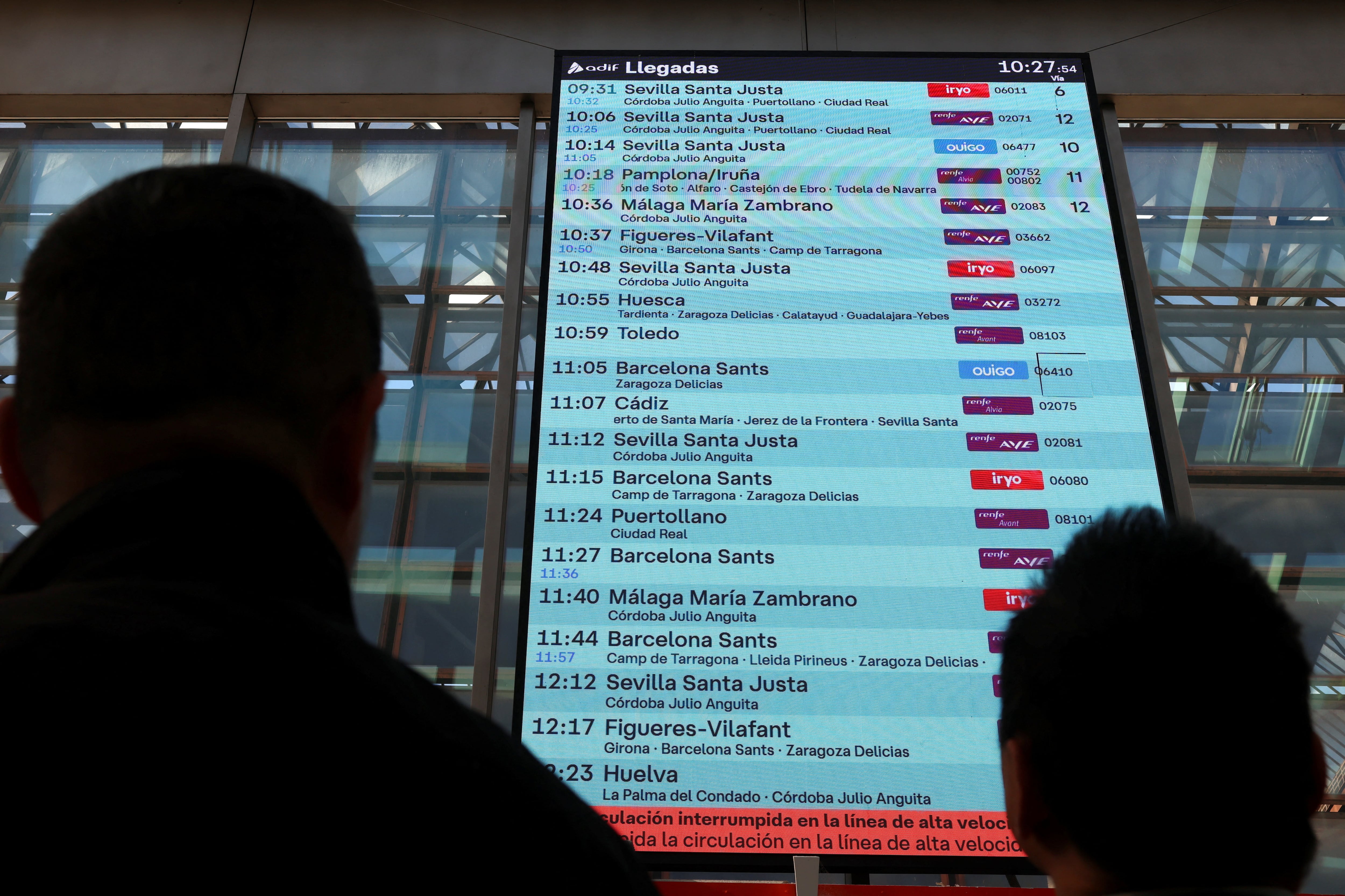Varias personas consultan una pantalla informativa en la que se muestra un mensaje que indica que el servicio de tren de alta velocidad entre Madrid y Andalucía ha quedado interrumpido. (REUTERS/Susana Vera)