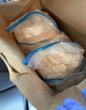 Dos bolsas de plástico transparente con cierre hermético llenas de sustancia cristalina dentro de una bolsa de papel marrón