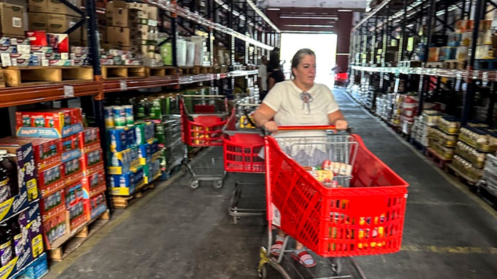 Una compradora empuja su carro en una tienda de comestibles privada, a la que se conoce como el