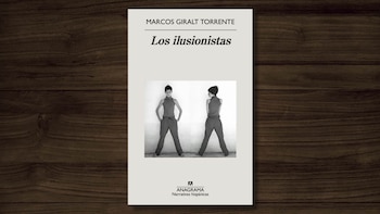 Una copia del libro 'Los ilusionistas' de Marcos Giralt Torrente, con una cubierta en blanco y negro de dos figuras, sobre una superficie de madera oscura