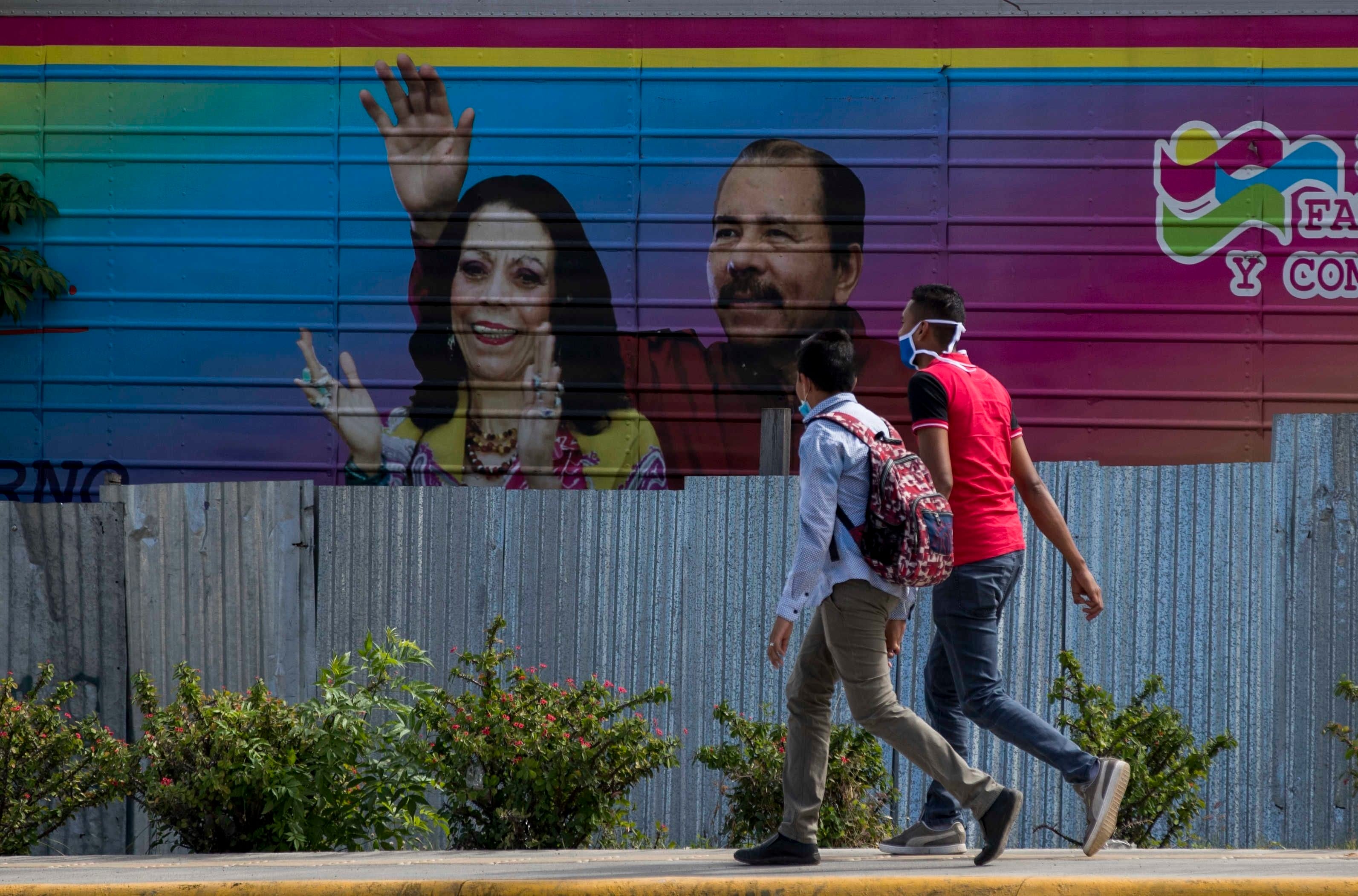 Dos jóvenes fueron registrados al caminar frente una pancarta con la imagen del presidente de Nicaragua, Daniel Ortega (d), y su esposa, Rosario Murillo (i), en Managua (Nicaragua). EFE/Jorge Torres