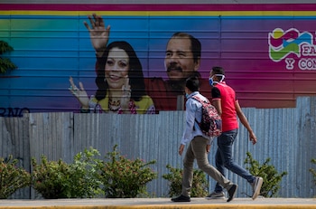 Dos jóvenes fueron registrados al caminar frente una pancarta con la imagen del presidente de Nicaragua, Daniel Ortega (d), y su esposa, Rosario Murillo (i), en Managua (Nicaragua). EFE/Jorge Torres