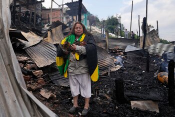 Verónica Kupto junto a las gallinas rescatadas entre los escombros carbonizados de su casa después de un incendio en Bogotá - crédito Fernando Vergara/AP