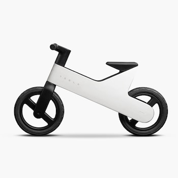 Bicicleta de equilibrio blanca y negra con el logo de Tesla en el cuadro. Tiene dos ruedas negras, un asiento negro y un manillar negro. Fondo blanco