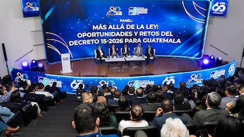 Cinco personas sentadas en un escenario frente a una pantalla gigante azul con texto sobre seguros, ante una audiencia en un auditorio