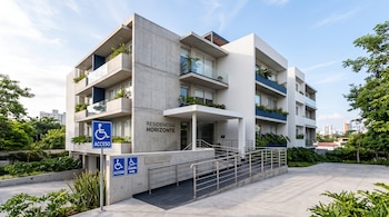 Fachada de un edificio de tres pisos con rampa de entrada y carteles azules con el símbolo internacional de accesibilidad.
