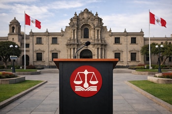 Podio vacío con micrófono y logo del JNE, frente a la fachada monumental de la Universidad Nacional Mayor de San Marcos, con banderas de Perú ondeando.
