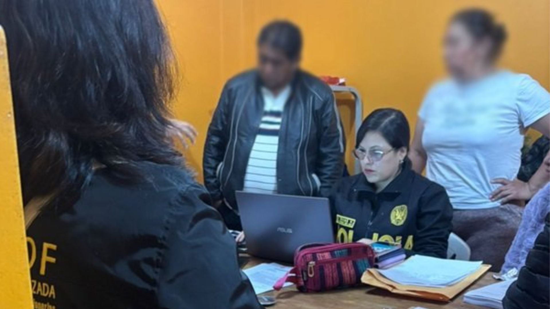 Una agente de la Policía Nacional del Perú en Ayacucho revisa datos en una laptop, acompañada por otras personas, durante una investigación o diligencia policial en la región. (PNP)