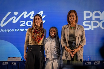 Tres mujeres sonríen de pie frente a un panel azul con los logos de Lima 2027 y Panam Sports, y un cartel con el nombre de Erica Lang