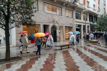 Varias personas se protegen de la lluvia caída este lunes en Santander. (EFE/Román G. Aguilera)