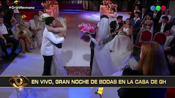 Una pareja se besa en el centro de una ceremonia de bodas con otra pareja, varios invitados sentados, y arreglos florales
