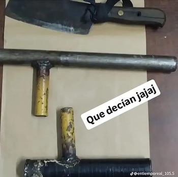 Una vista aérea de un cuchillo grande tipo machete y dos objetos contundentes metálicos de fabricación casera sobre una superficie clara y oscura