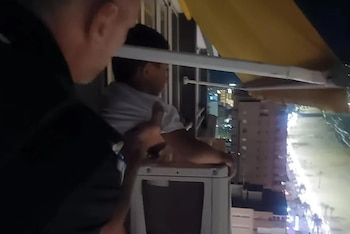 Momento en el que un agente de la Policía Local de Benidorm rescata al menor que se encontraba sentando sobre un aire acondicionado. (Policía Local Benidorm)