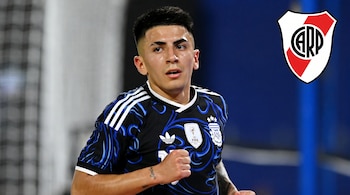 Primer plano de un futbolista joven con cabello oscuro, usando una camiseta negra y azul de Argentina. Se ve el escudo de River Plate arriba a la derecha.