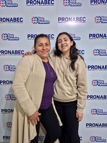 Una joven con brackets sonríe junto a su madre, quien la abraza, frente a una pared con los logos repetidos de Pronabec y el lema 'Soy Talento'