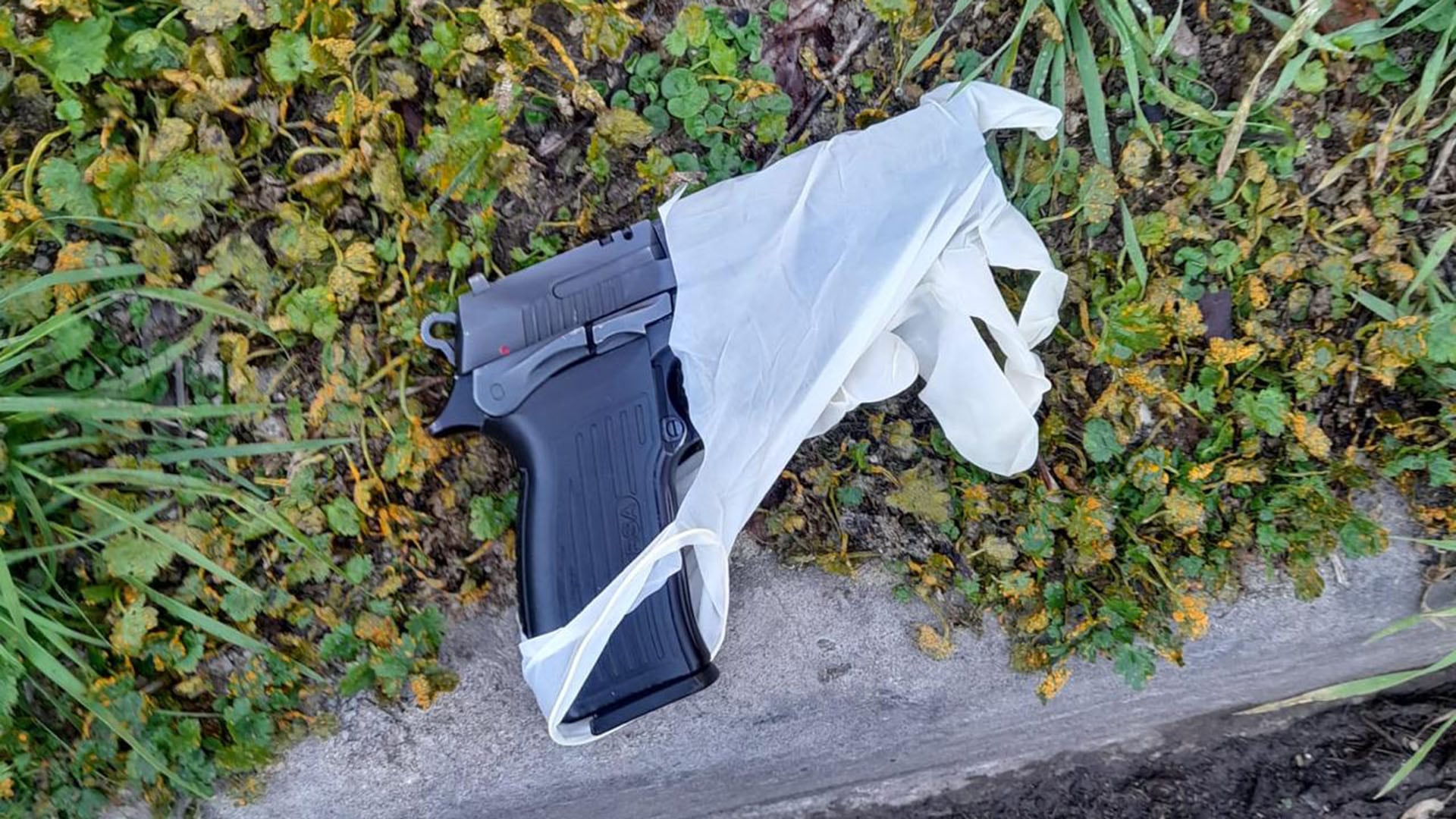 Un arma de fuego cubierta parcialmente por un guante de látex yace en el suelo tras un ataque a tiros registrado en la localidad de El Palomar.