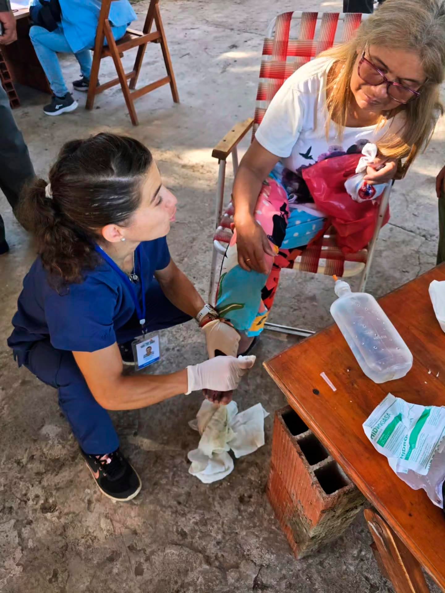 La judoca Paula Pareto, vestida con uniforme médico, atiende a una persona sentada en una silla, en Chaco