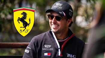 Sergio Pérez sonríe con gafas de sol, gorra y chaqueta junto al escudo amarillo de Ferrari.