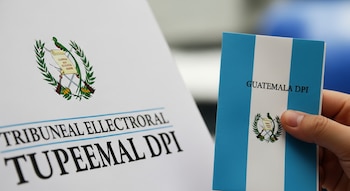Mano sostiene documento con 'GUATEMALA DPI', bandera y escudo nacional, frente a hoja con el logo del Tribunal Supremo Electoral.