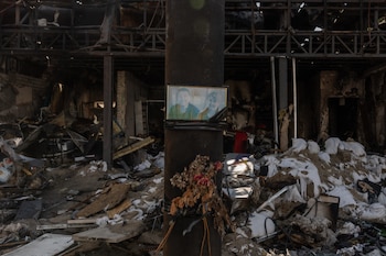 Un retrato de víctimas colocado en una gasolinera destruida por un ataque aéreo ruso en la ciudad de Izium, en la región oriental de Járkov (Roman PILIPEY / AFP)