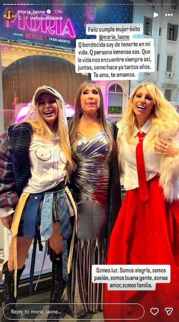 Tres mujeres sonríen a cámara. La central lleva vestido plateado. La de la izquierda usa gorro, chaqueta a cuadros y falda de corbatas. La de la derecha, vestido rojo