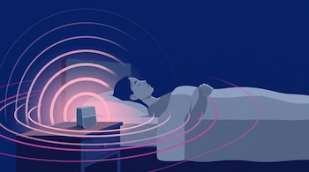 Una persona duerme en una cama junto a un altavoz compacto sobre la mesa de noche, del cual emergen ondas sonoras rosadas y magentas.