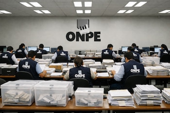 Vista amplia de una sala de cómputo de la ONPE con funcionarios de espaldas en chalecos azules revisando documentos en mesas largas con actas y urnas. El logo de ONPE está en la pared.