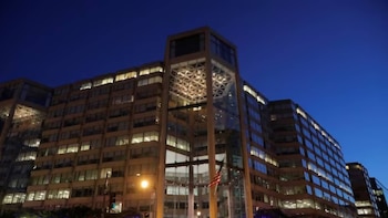 Edificio moderno de la American Bar Association con numerosas ventanas iluminadas al anochecer, una bandera estadounidense ondea en la entrada