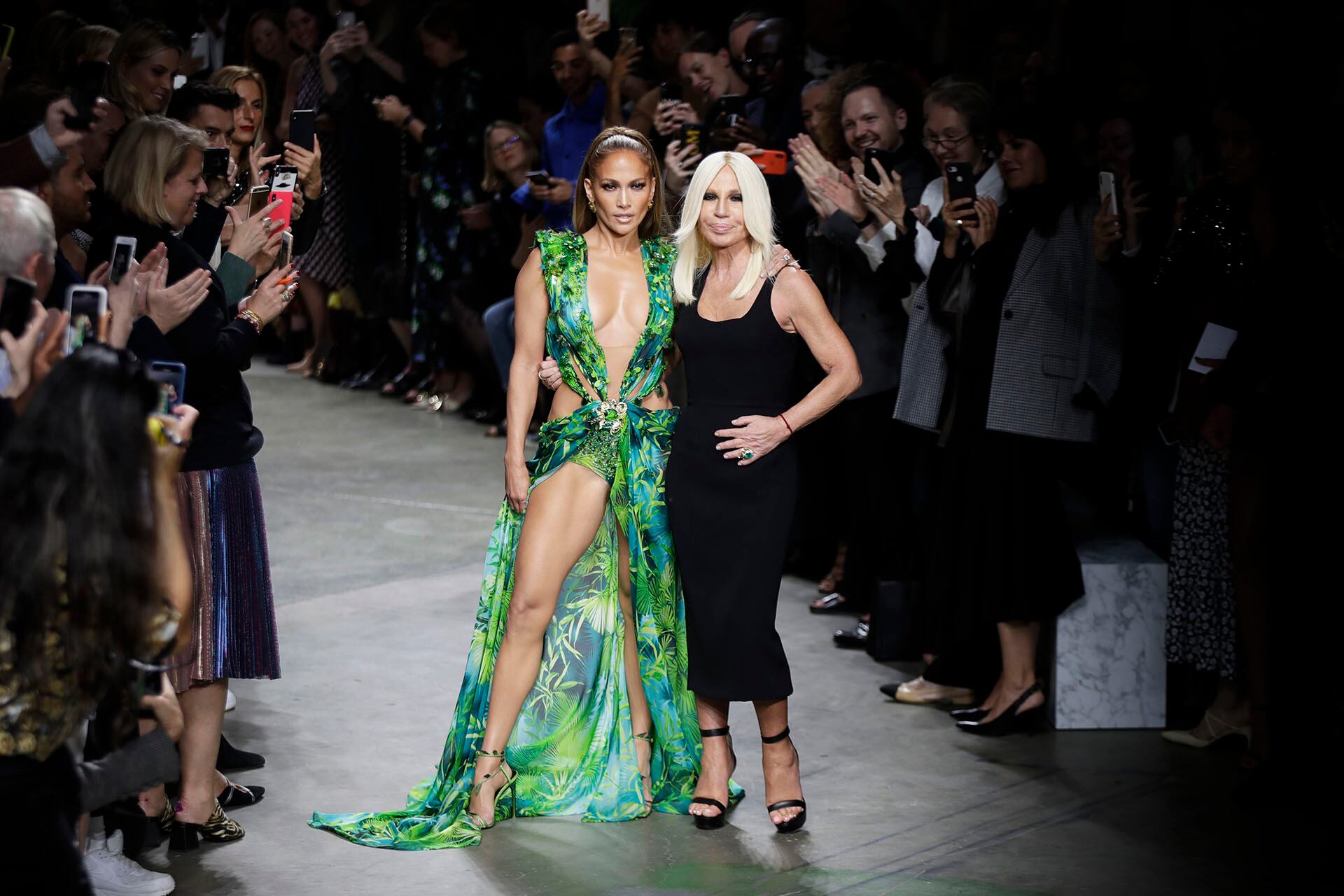La actriz Jennifer Lopez, a la izquierda, y la diseñadora Donatella Versace reciben aplausos al concluir la colección Primavera-Verano 2020 de Versace, presentada durante la semana de la moda en Milán, Italia, el viernes 20 de septiembre de 2019. (Foto AP/Luca Bruno)